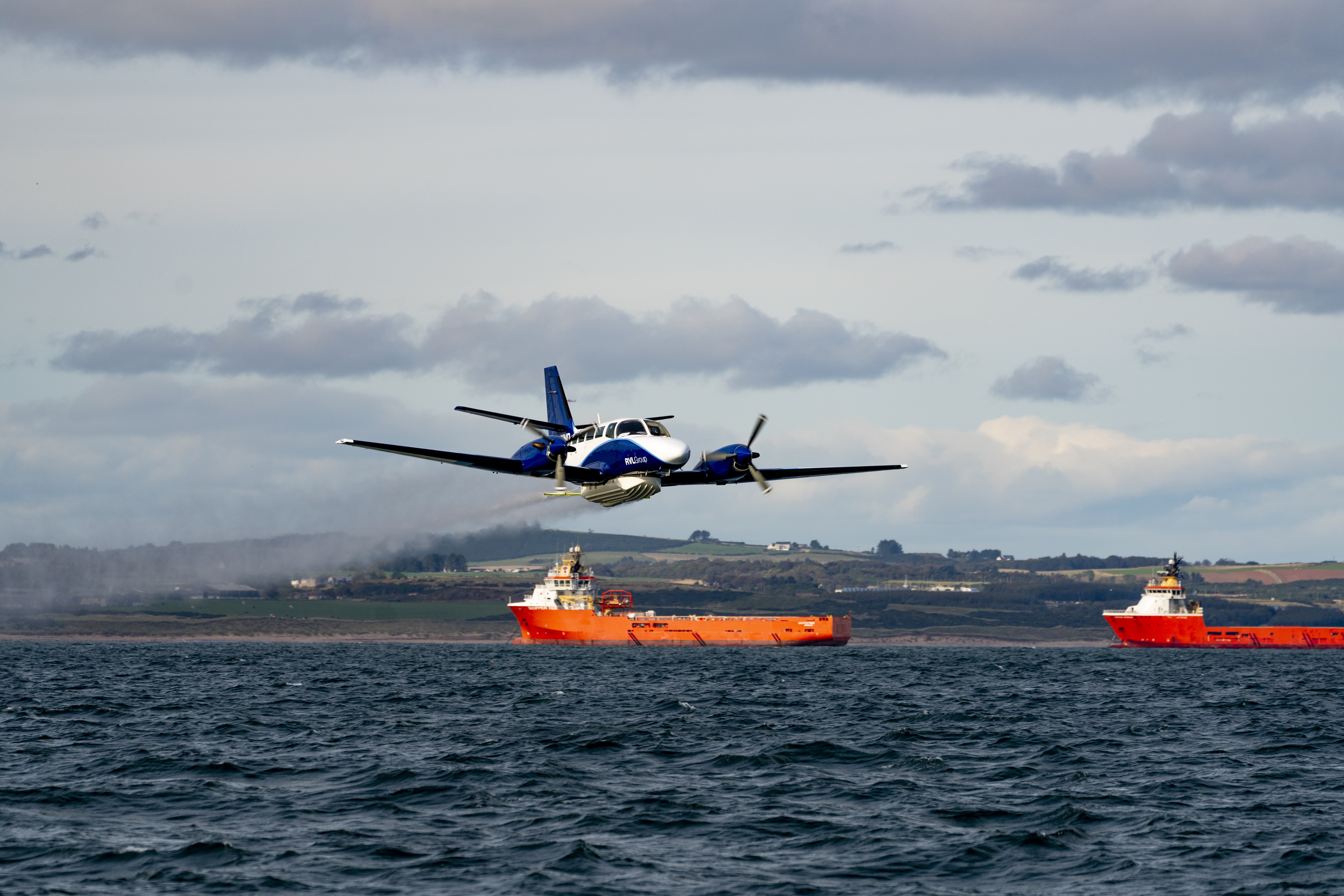 A small plane plane flies over the sea spraying mock dispersant