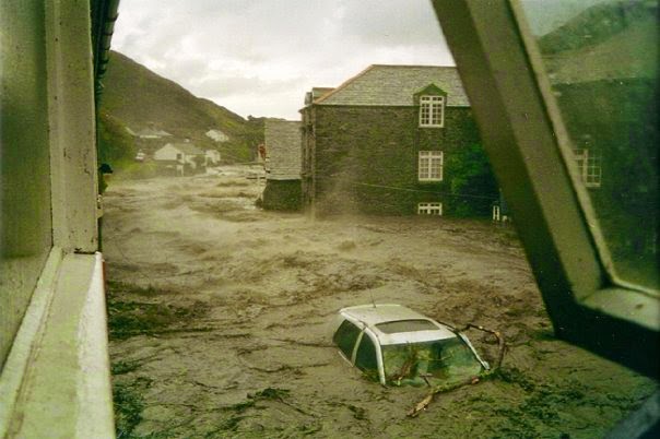 A car is carried by brown water along a flooded street