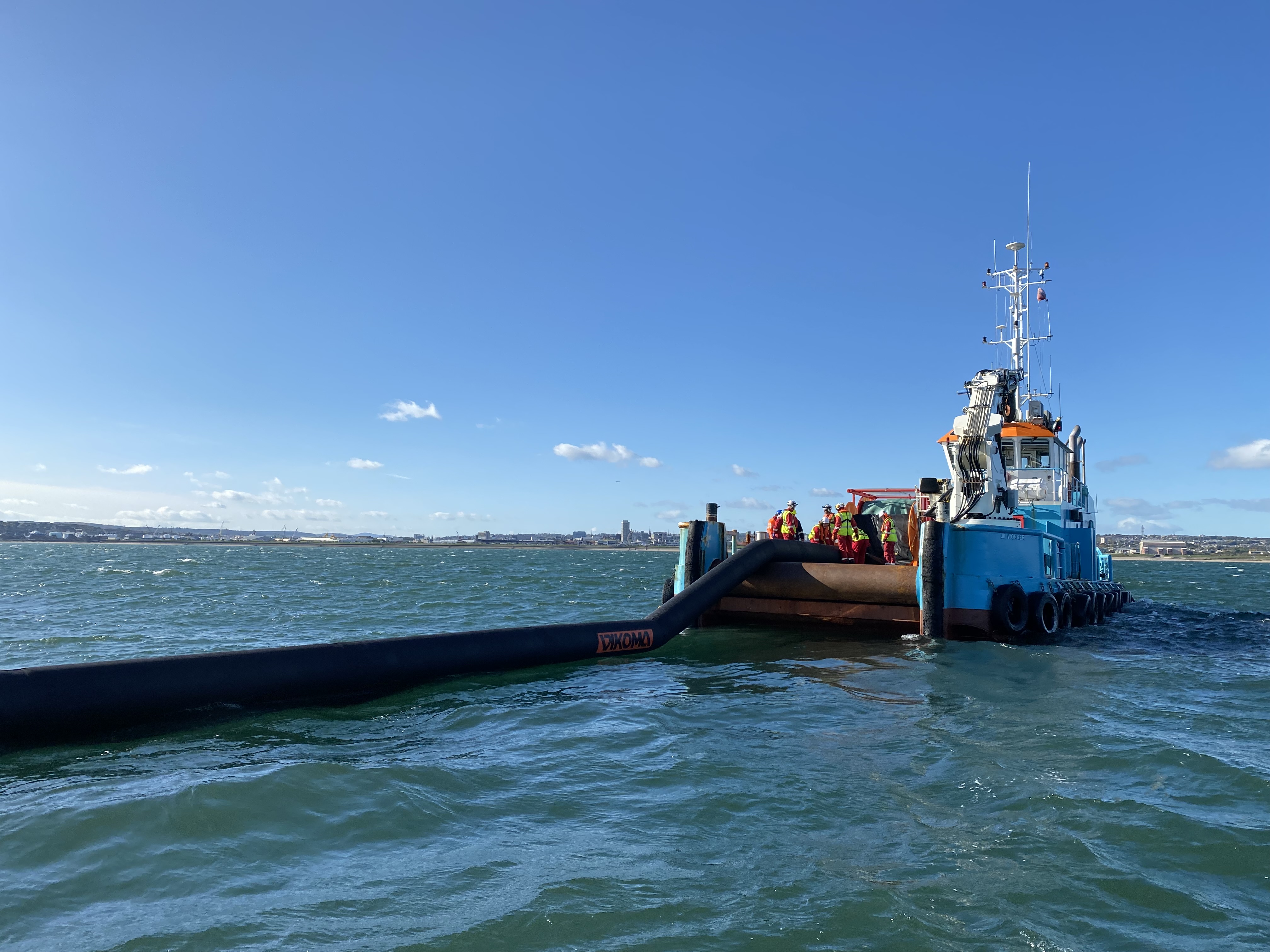 A vessel running out a black, inflated, counter pollution boom