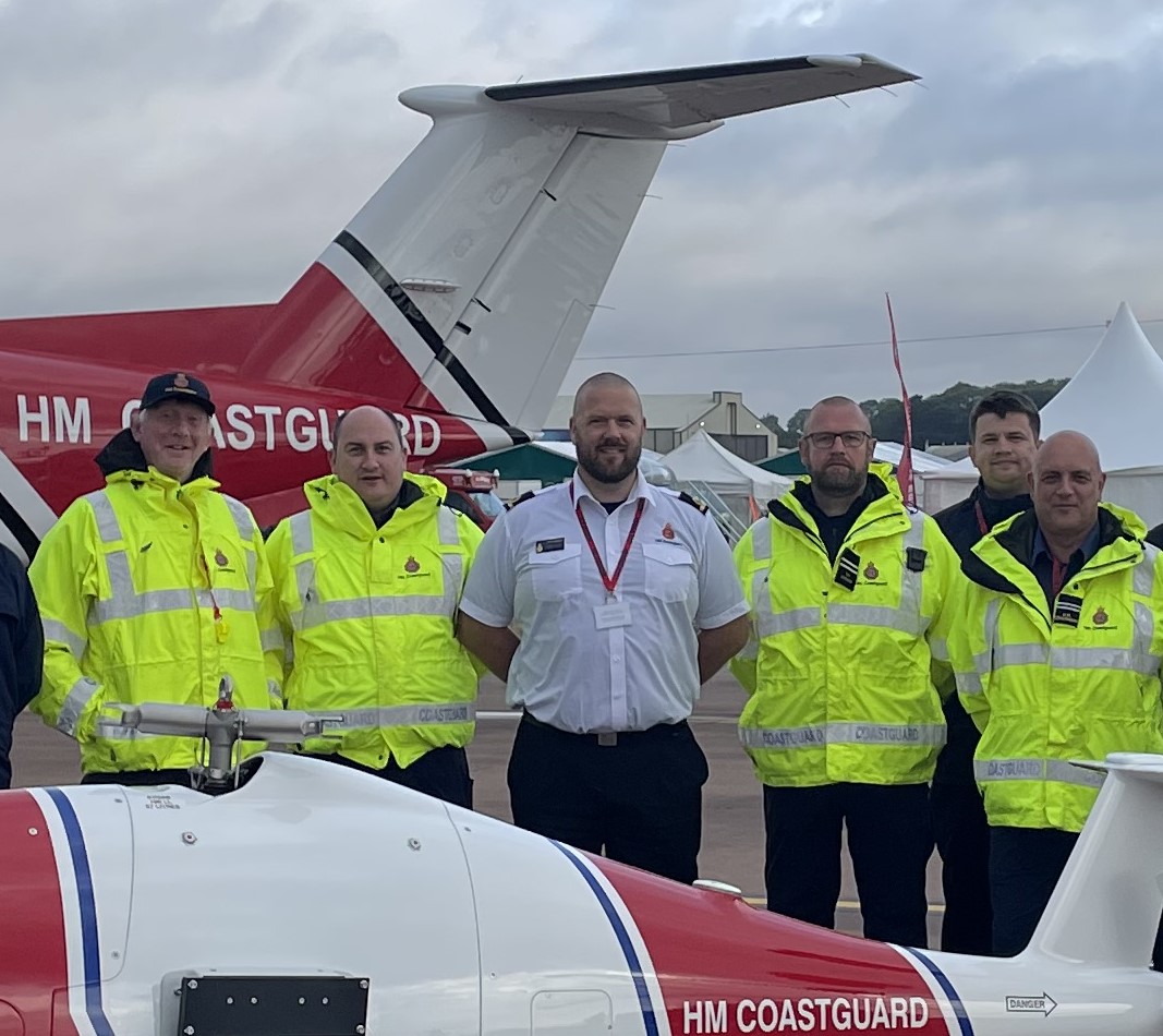 Five men posing for camera. Four in high vis jackets and man in middle in white shirt