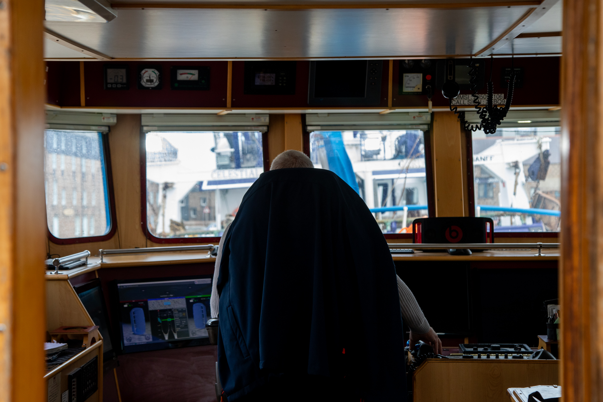 Bruce Mitchell, viewed from behind, as he sits on the bridge of his new fishing vessel