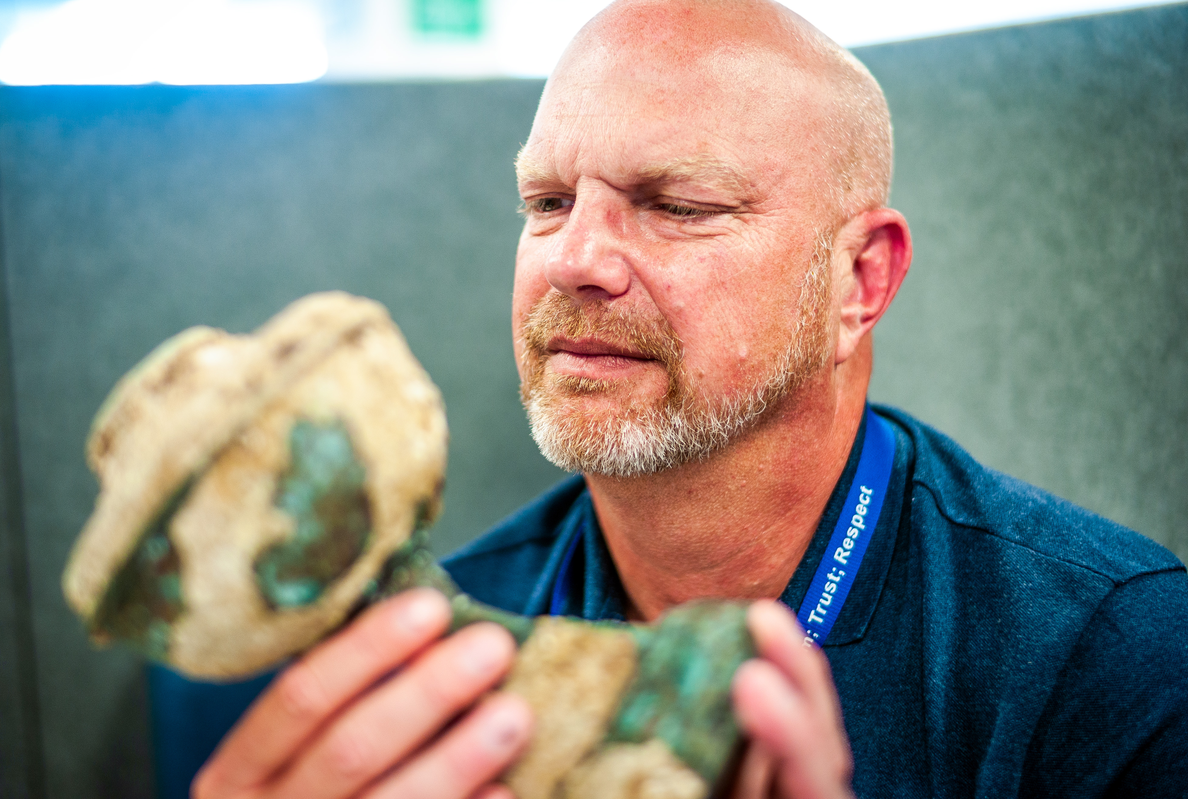 Steve White looks at a tarnished copper chalice shipwreck item 