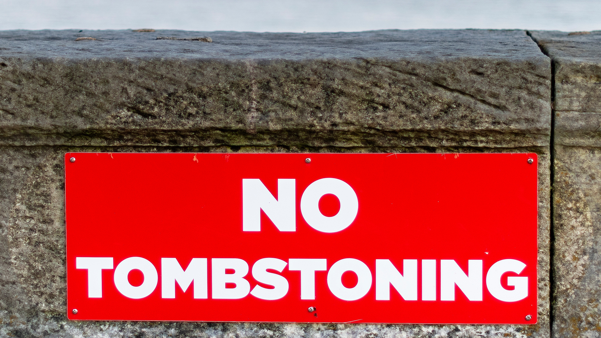 A red 'no tombstoning' sign on a shoreside wall