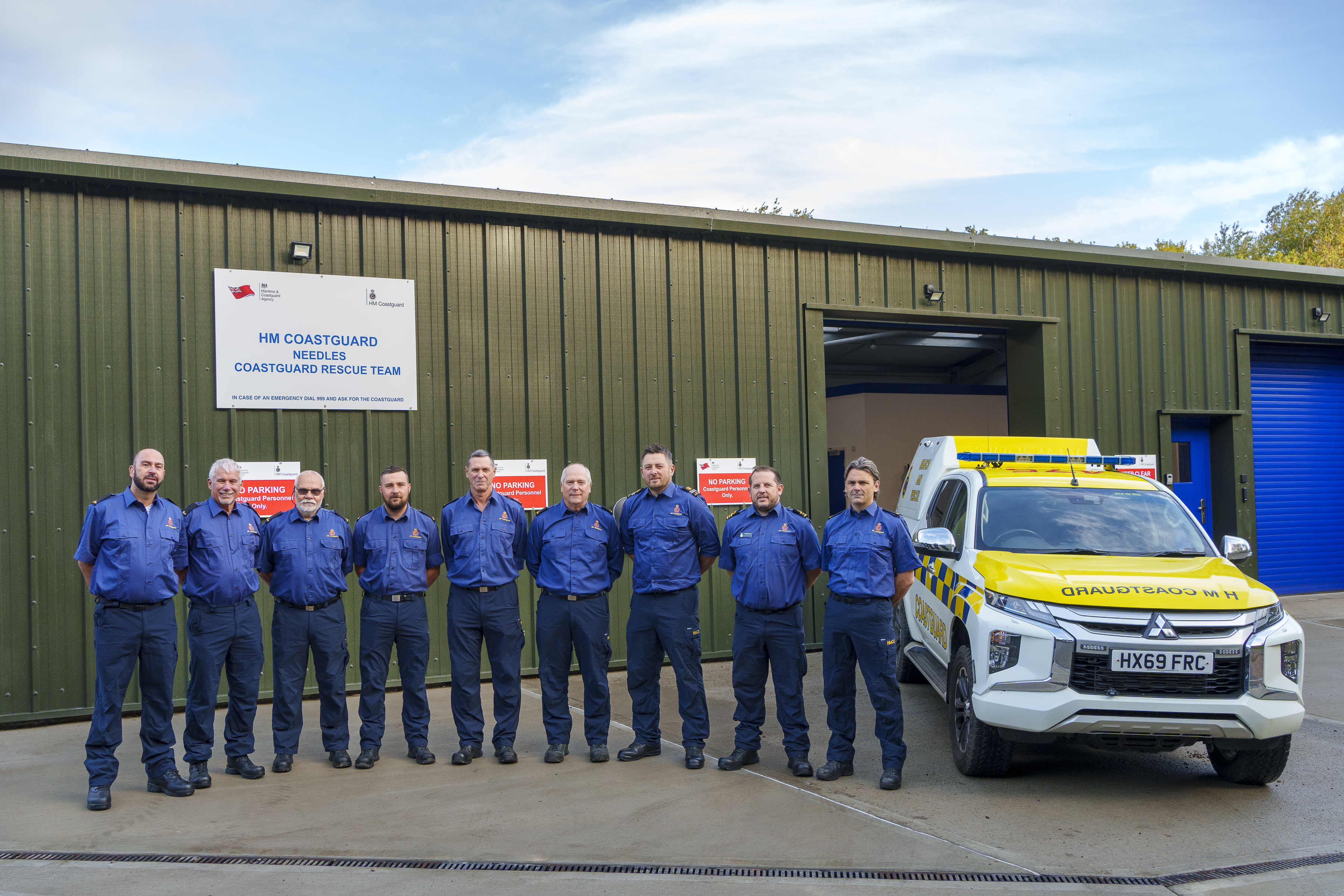 Members of Needles Coastguard Rescue Team stood outside new station next to coastguard vehicle