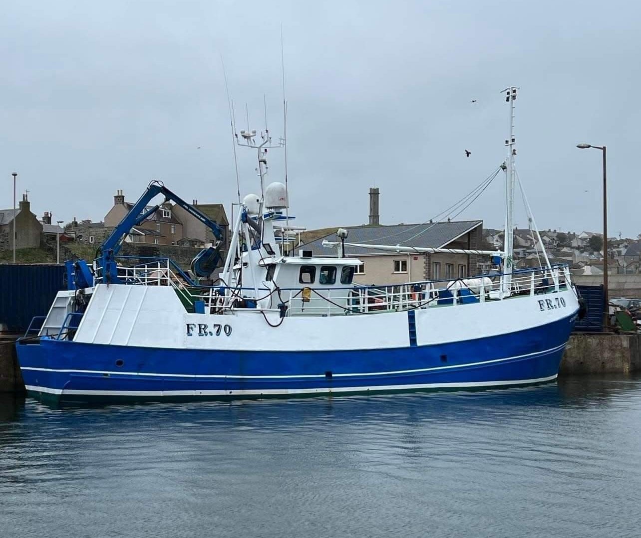 The blue and white fishing vessel Odyssey moored by a quay