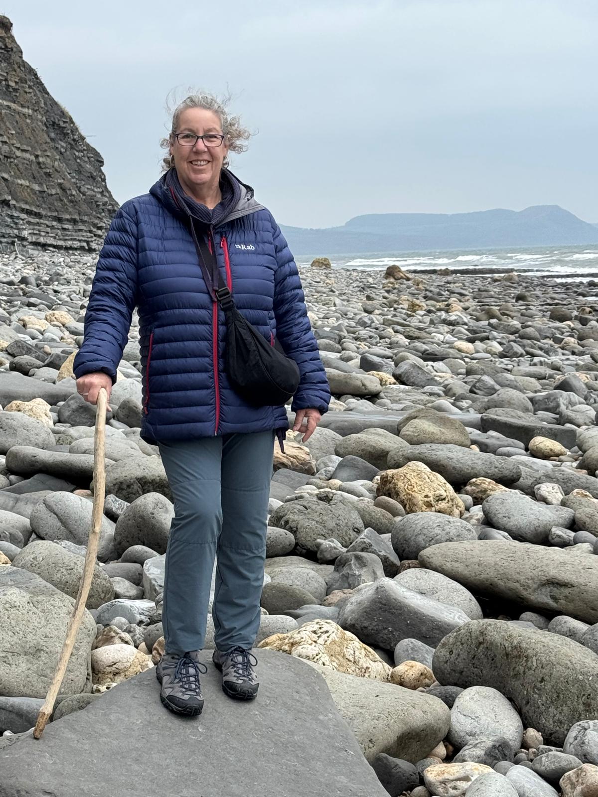 Philippa O'Brien standing with a beach of boulders behind her