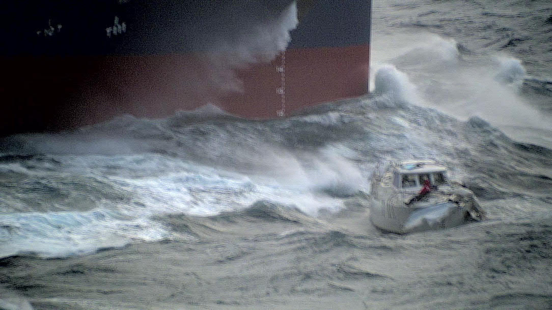 The stricken sailing yacht in the Atlantic Ocean, with the first responding recovery vessel approaching