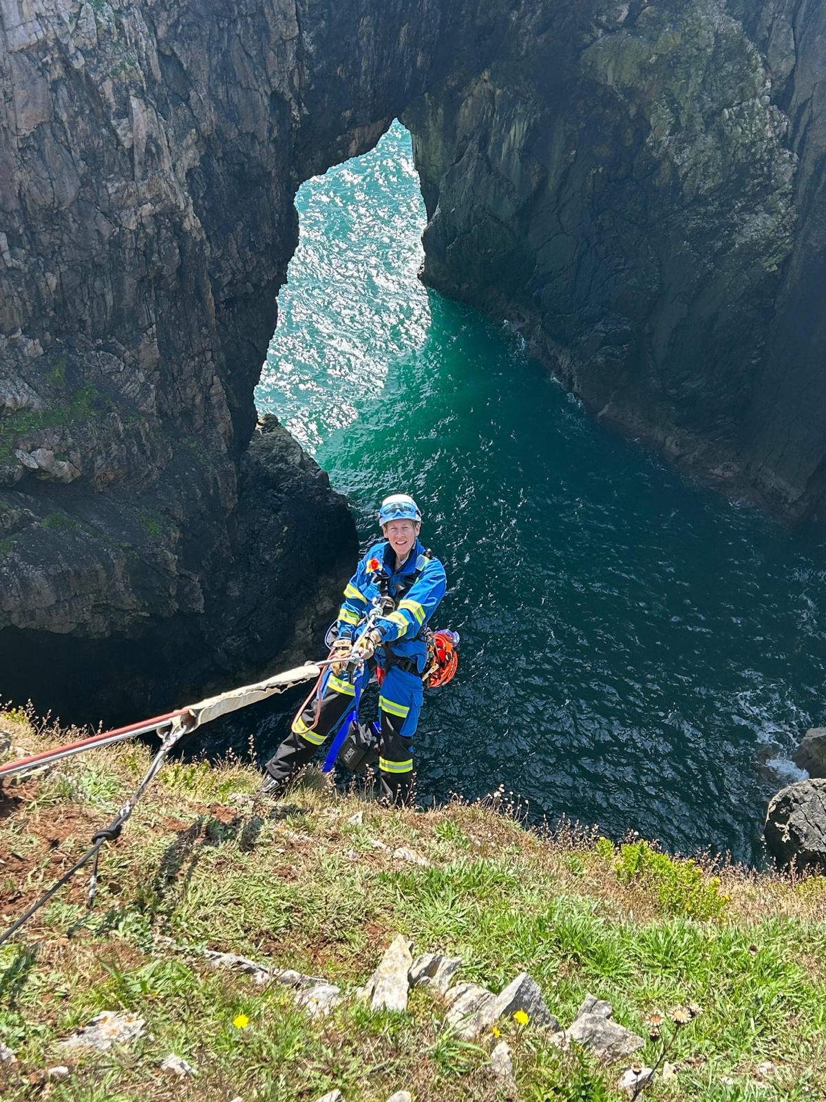Senior Coastal Operations Officer Bex Owen, dangling over a cliff in Devils Cauldron, Wales, as part of a rope exercise