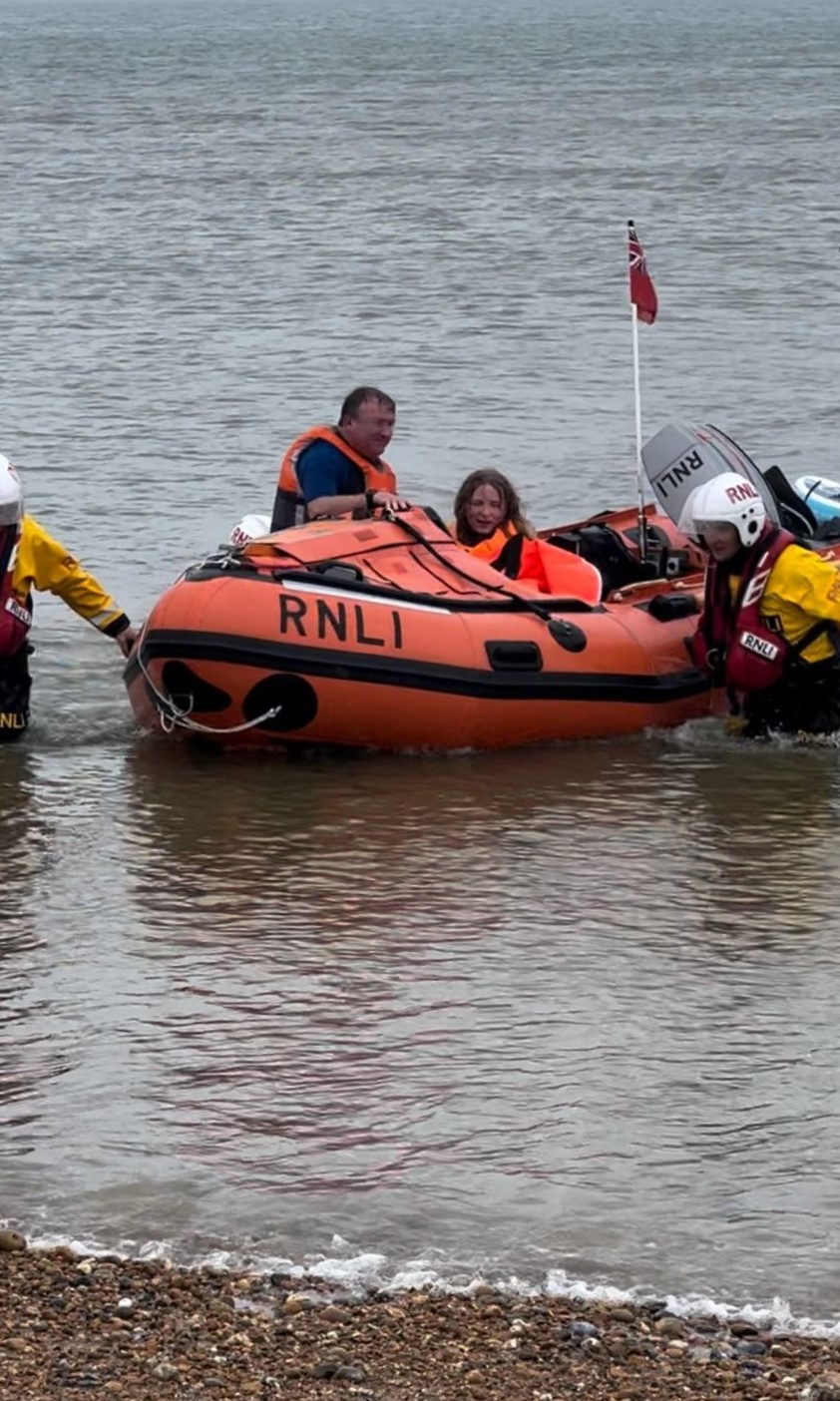 Steve and Alyssa are brought to shore on an RNLI inshore lifeboat with two crew helping