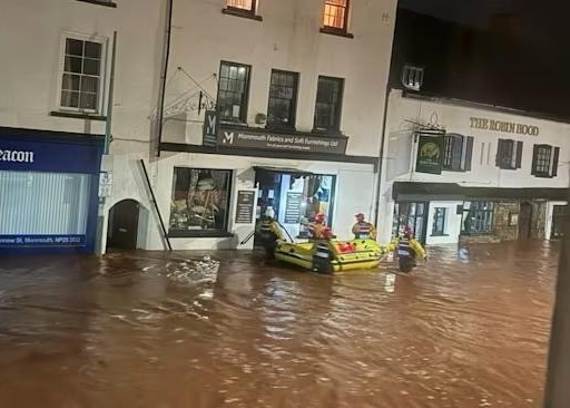 Coastguards steer a life raft down a flooded street