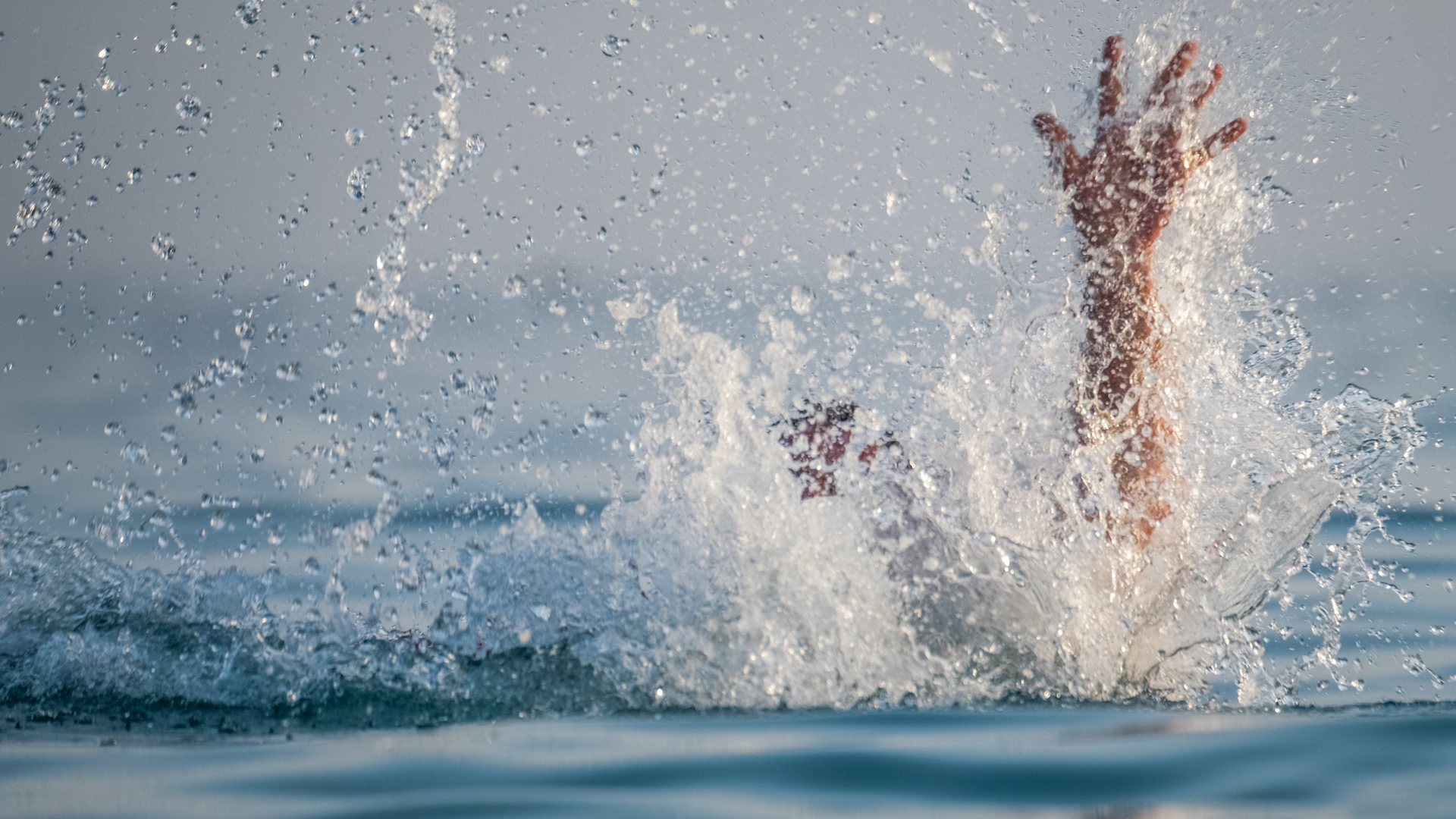 A pair of panicked arms splash above the water