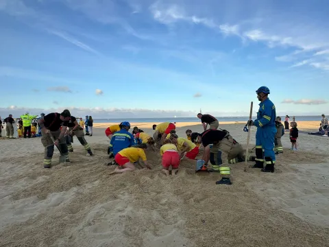 Firefighters, lifeguards and Coastguard Rescue Officers practice a sand hole rescue