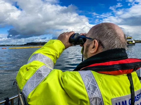 A Counter Pollution and Salvage officer watches out to sea through binoculars