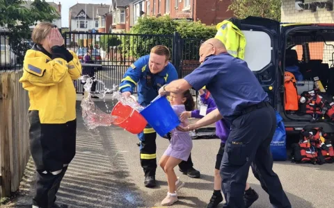 Miss Mills wears HM Coastguard kit as a bucket of water is thrown at her by two coastguards and a pupil