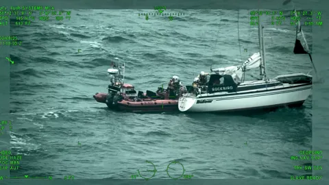 An RNLI lifeboat rescuing Richard Spreckley from his vessel during rough sea conditions