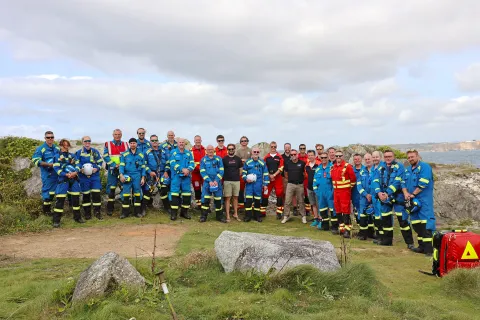 A group photo by the cliff of Coastguard Rescue Officers and Cornwall Air Ambulance personnel