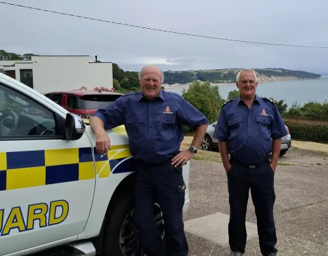 Roger and Terry posing in front of a HM Coastguard vehicle in 2025. 