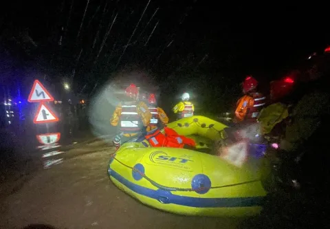 Coastguards steer a life raft through flood water