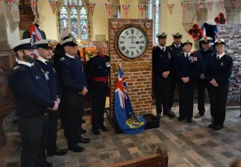 Coastguards stand either side of the memorial clock at St Nicholas Withernsea