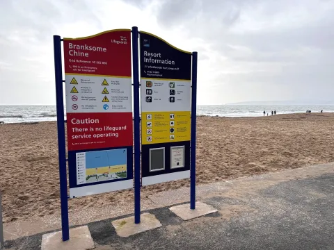 Image of a blue, yellow and white safety sign on a beach