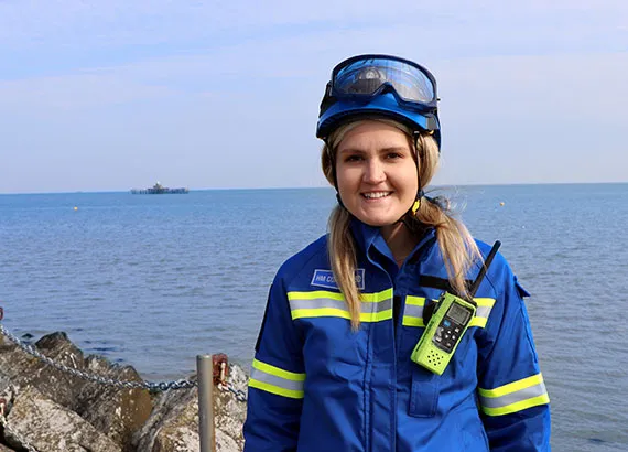 A female coastguard rescue officer standing in front of the sea