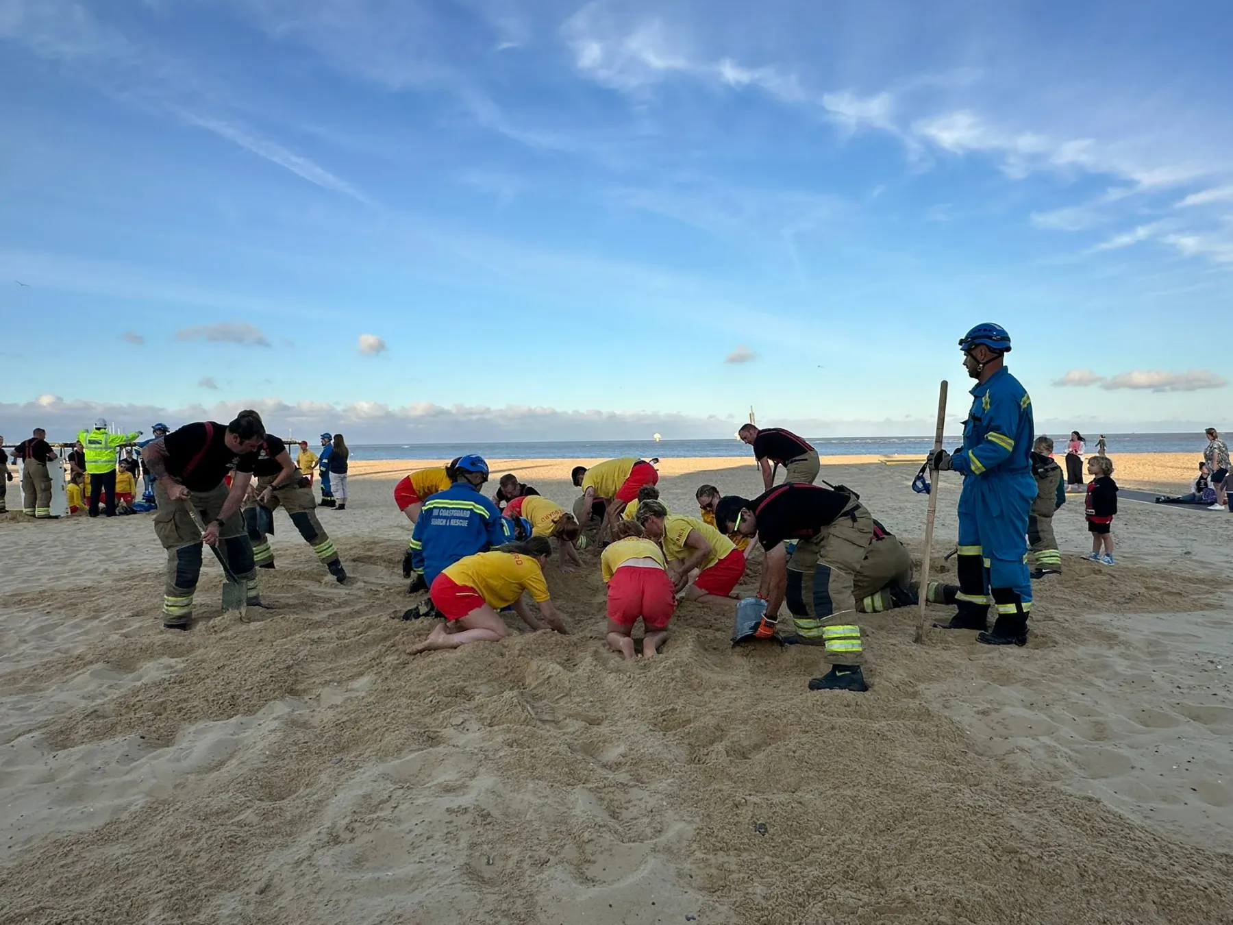 Firefighters, lifeguards and Coastguard Rescue Officers practice a sand hole rescue