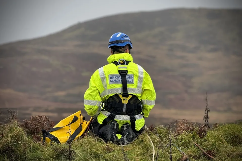 A coastguard rescue officer sat on the ground