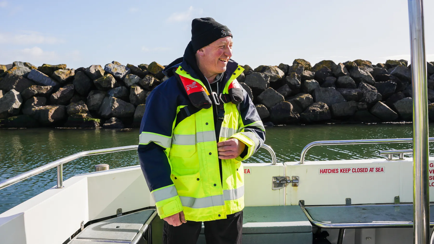 A man onboard a vessel with a hi-vis jacket and personal floatation device 