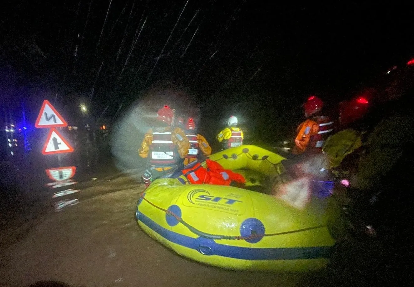 Coastguards steer a life raft through flood water