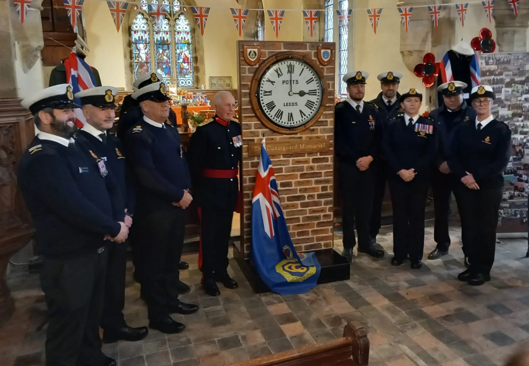 Coastguards stand either side of the memorial clock at St Nicholas Withernsea