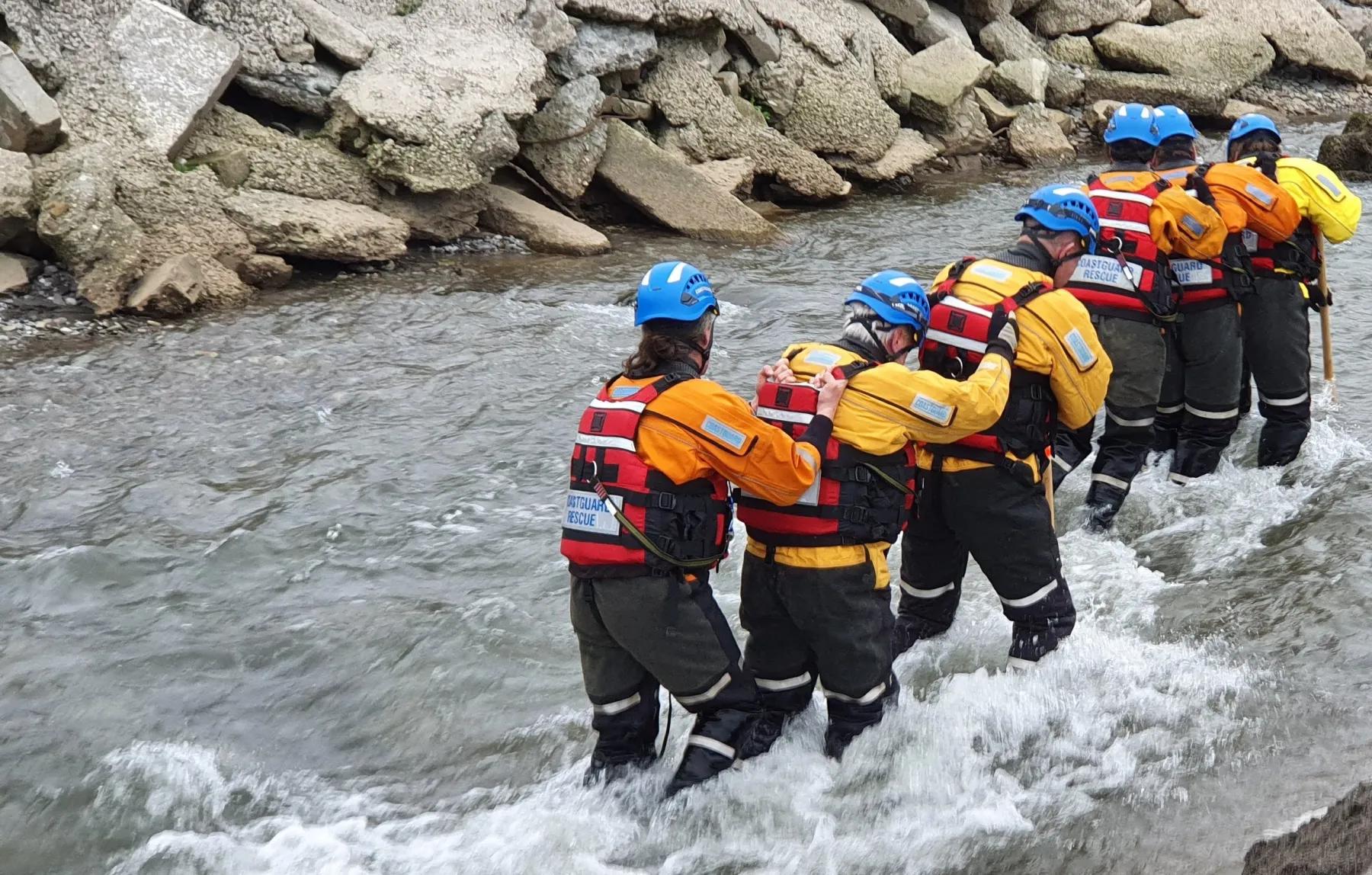 Tamar Coastguard Rescue Team wading through fast flowing water as part of a training exercise