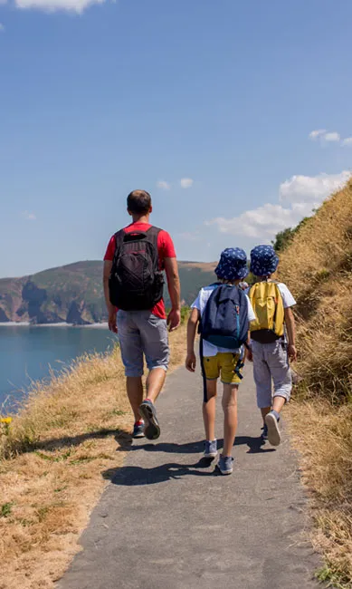 Father and sons walking along coastal path in summer