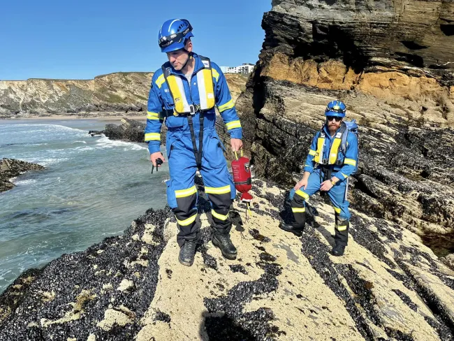 Coastguard Rescue Officers from Newquay Coastguard Rescue Team patrol rocks on the shore 