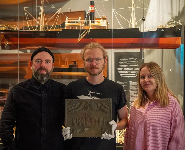 From left are Curators Jannik Hartrup and Curator Thorbjorn Thaarup, and Museum Assistant Mette Ebbesen in front of a model of the SS Viola, sister ship to the SS Birgitte