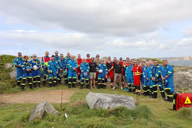 A group photo by the cliff of Coastguard Rescue Officers and Cornwall Air Ambulance personnel