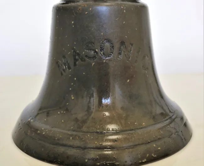 A close up picture of the bell bearing the ship name, Masonic
